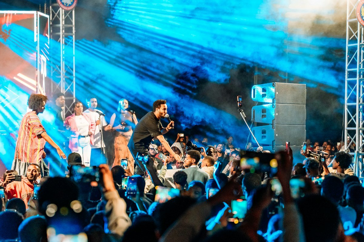 Le public d'un concert, bras levés sous les projecteurs bleus