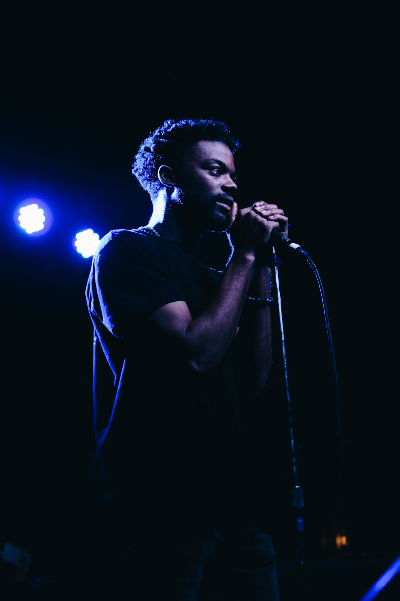 Un chanteur sur scène, micro en main, sous les projecteurs