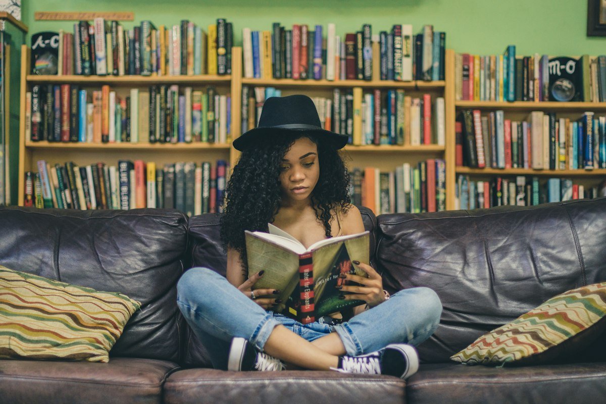 Une lectrice assise devant une bibliothèque