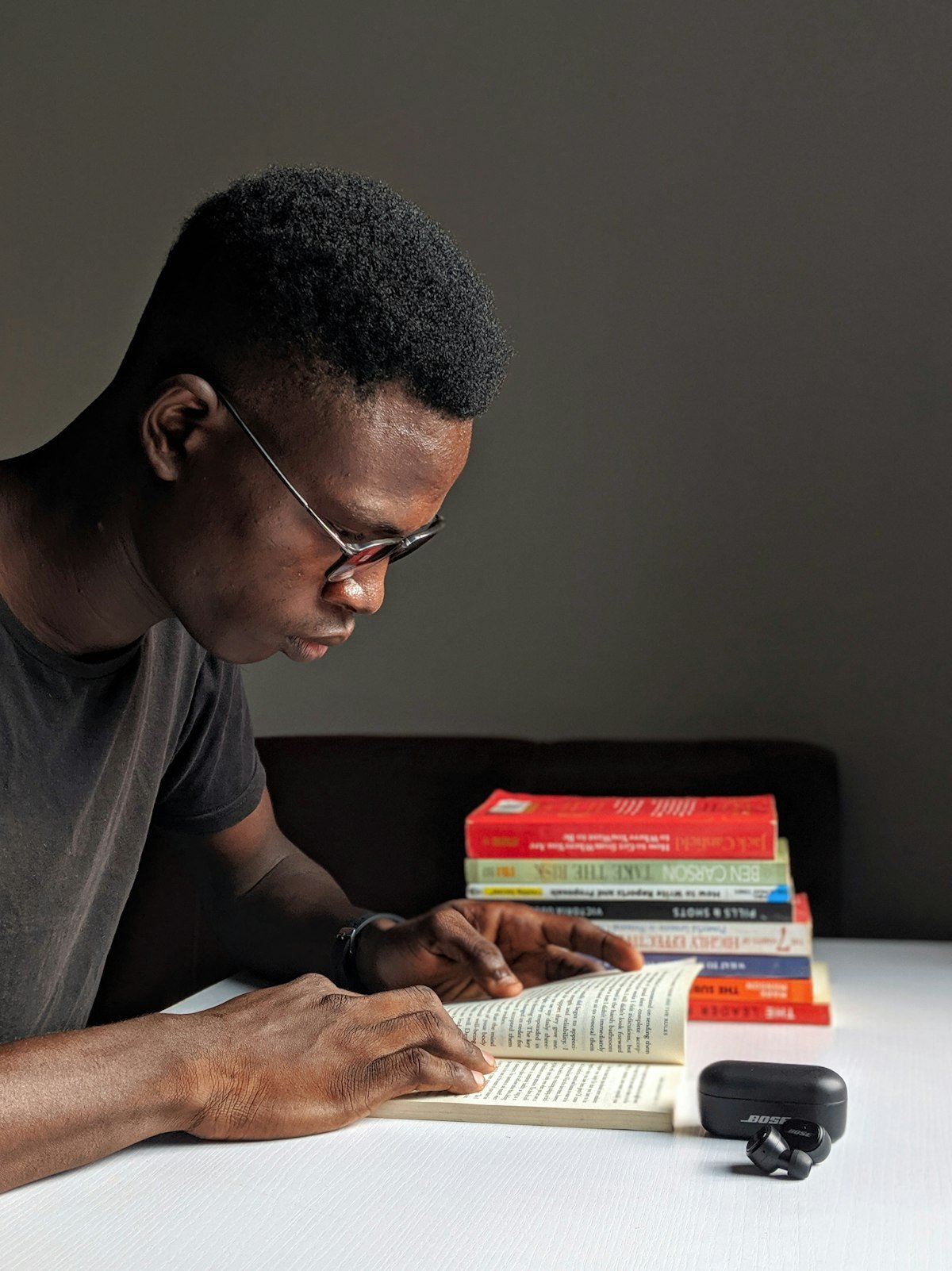 Un homme lit un livre, une pile d'ouvrages à côté de lui