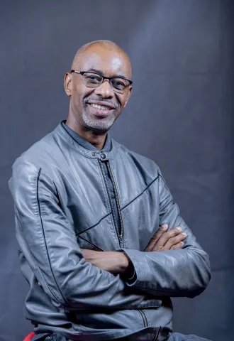 Portrait de Luc Mayitoukou, bras croisés, souriant