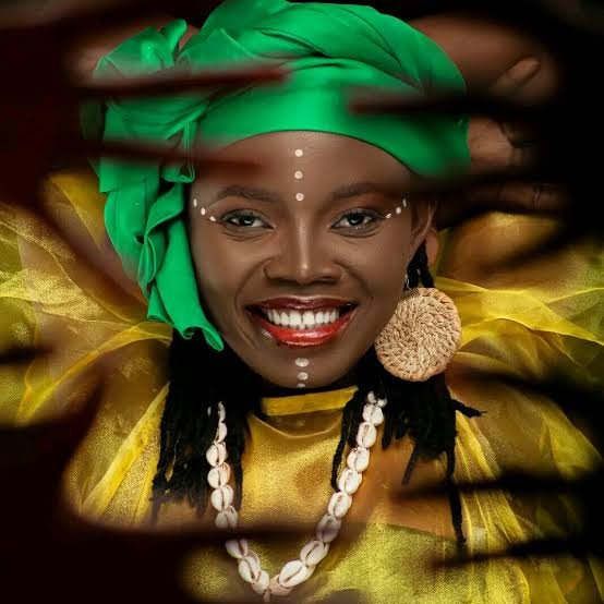 Mariusca, foulard vert, sourire éclatant, colliers de cauris