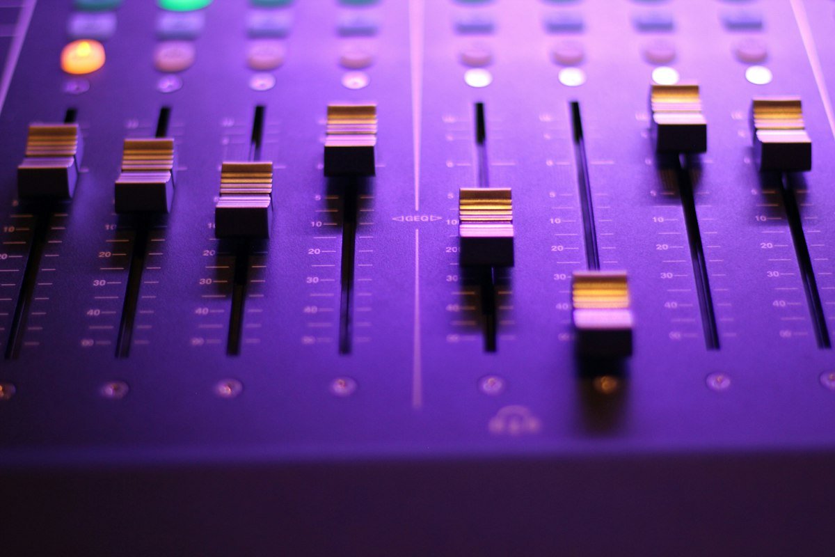 Les faders d'une console de mixage éclairés en violet