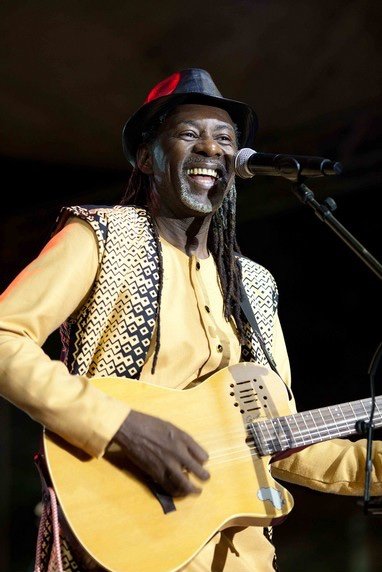 Saintrick sur scène, guitare en main, souriant au micro